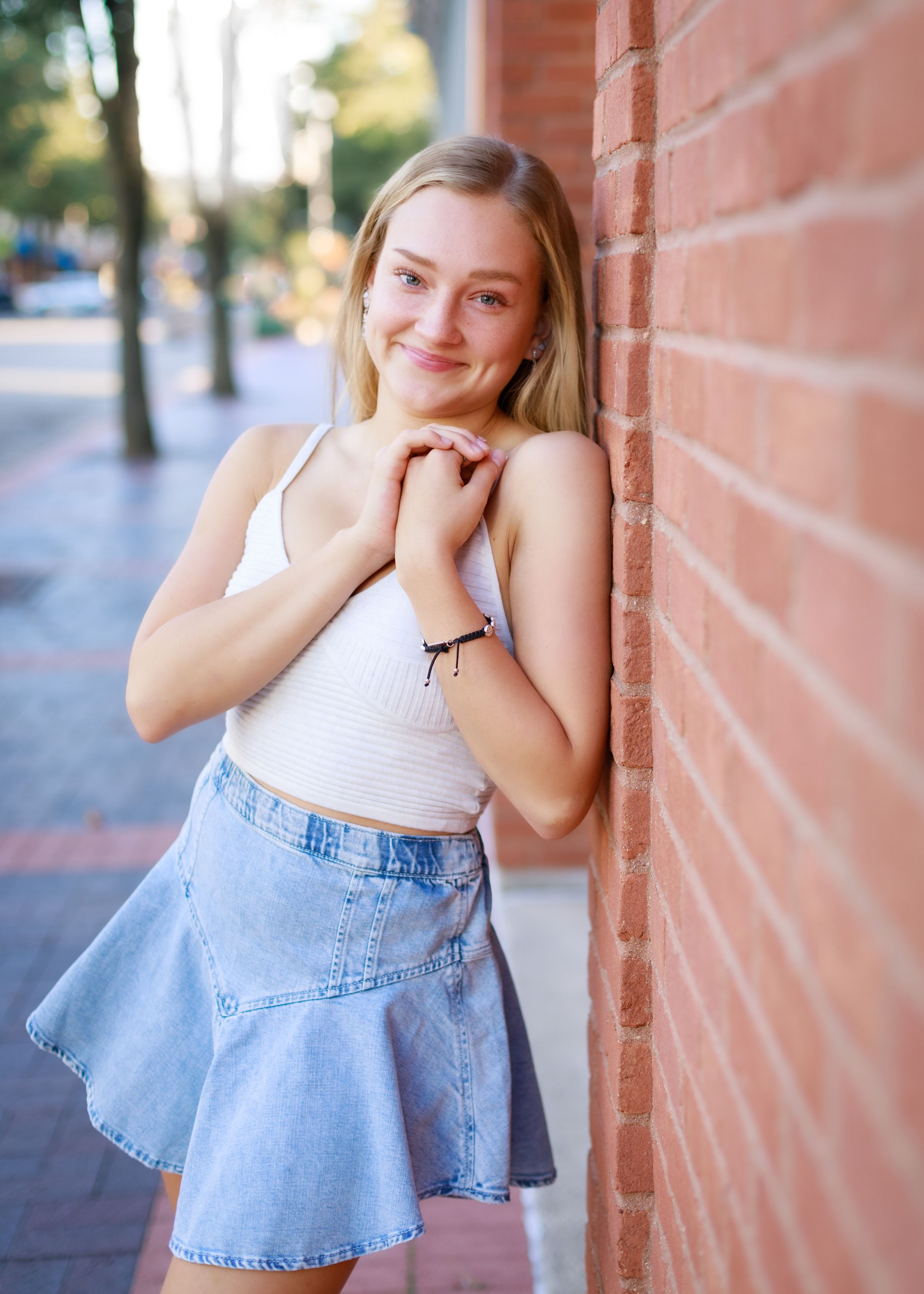 Fashion photo series showing a denim skirt and white top outfit against a brick wall backdrop.