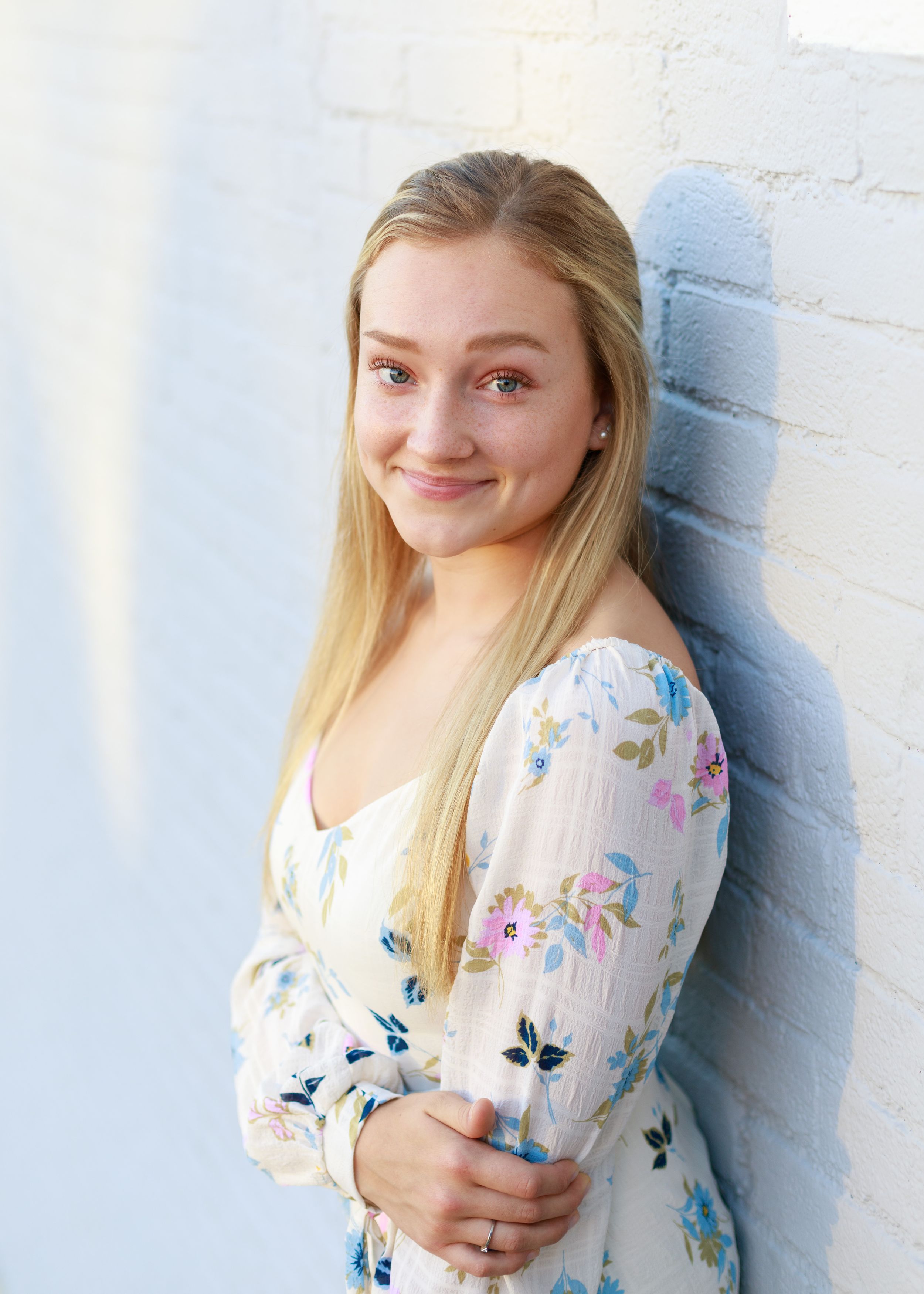 Portrait series featuring a floral print top with puff sleeves against a white wall.