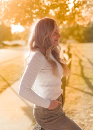 Golden hour portraits in white sweater with sunlit background.