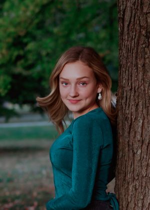Portrait series against a tree trunk showing playful poses in a dark teal sweater.
