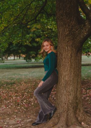 Playful poses against a large tree trunk in an autumn park setting.