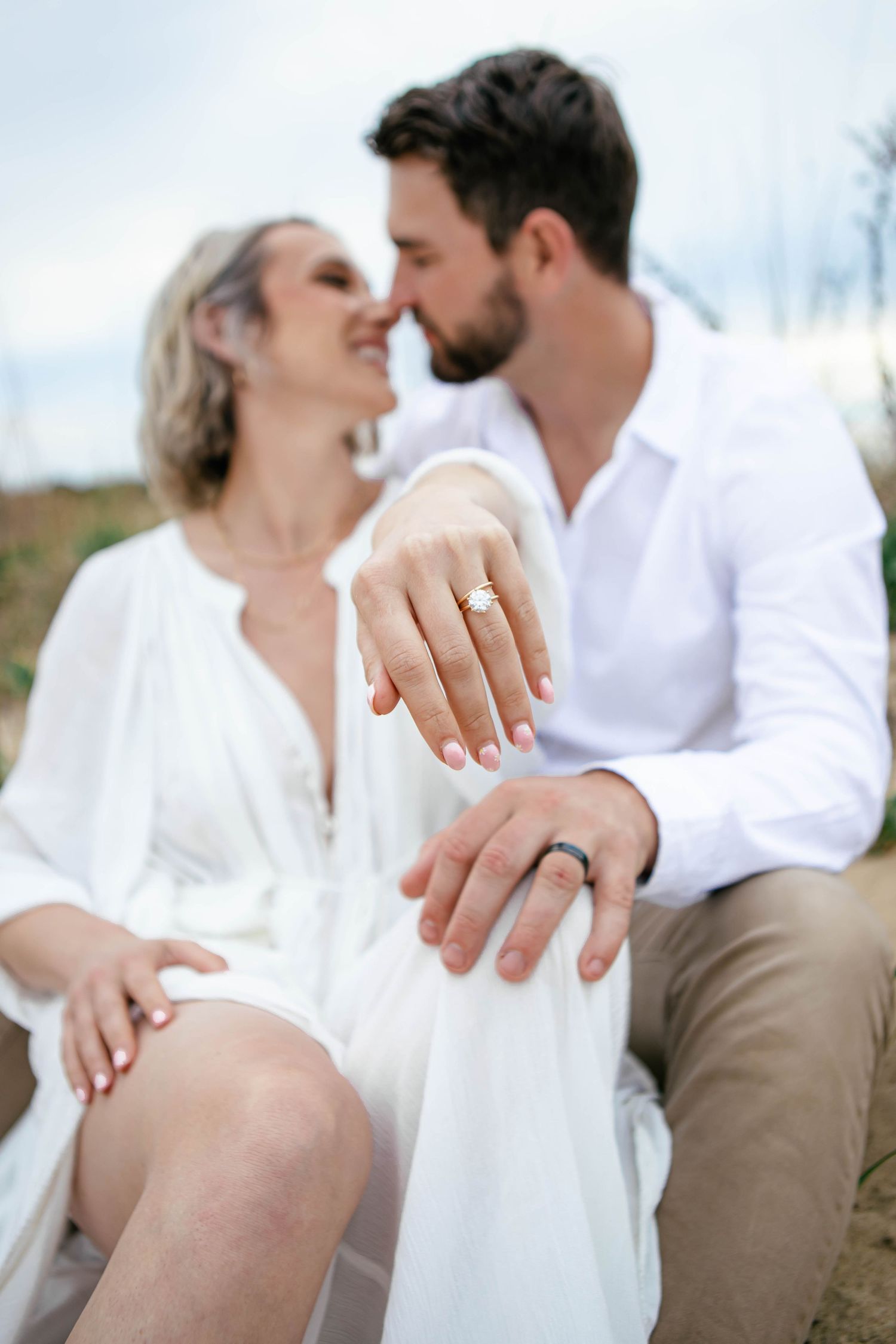 Intimate beach engagement photos showing ring and tender moments.