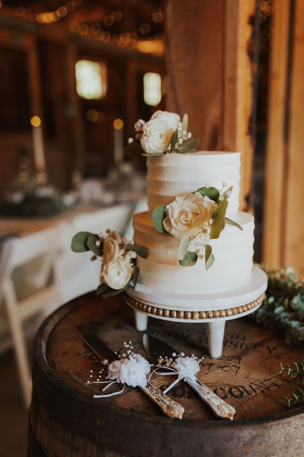 Elegant three-tier white wedding cake decorated with roses on rustic wooden stand in New Hampshire.