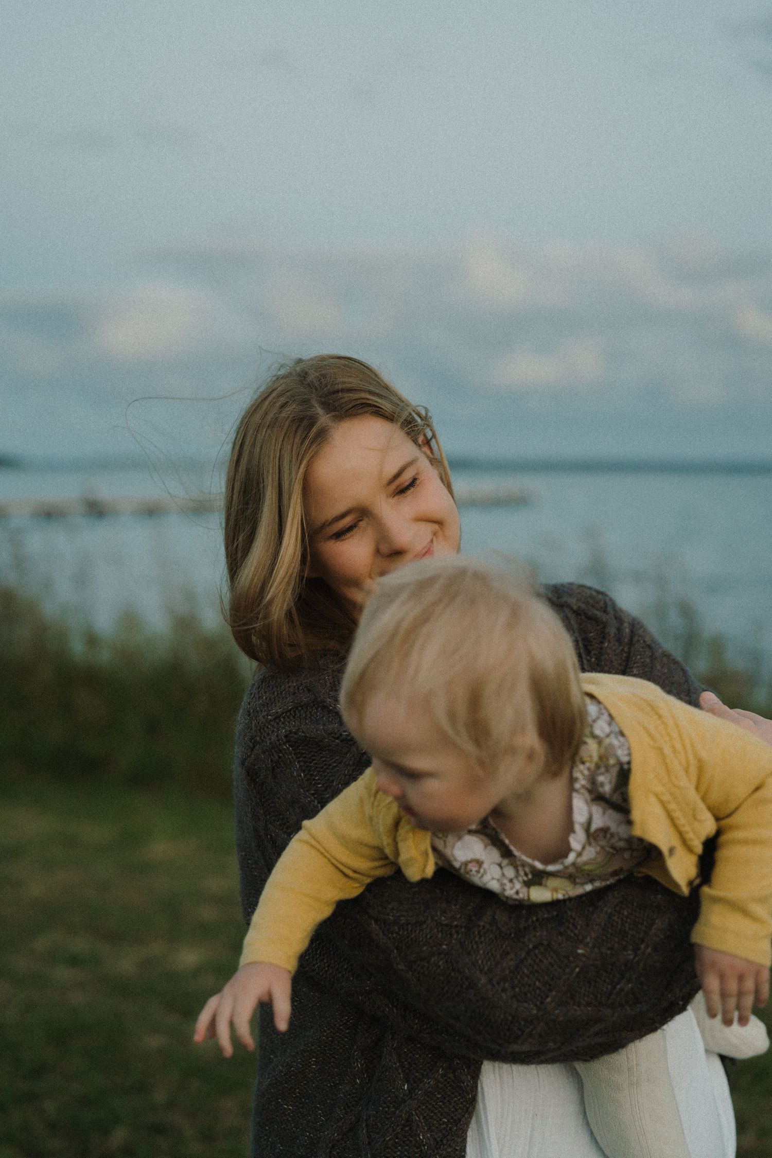 A tender moment captured in golden light showing a parent holding a small child with shadows on the wall.