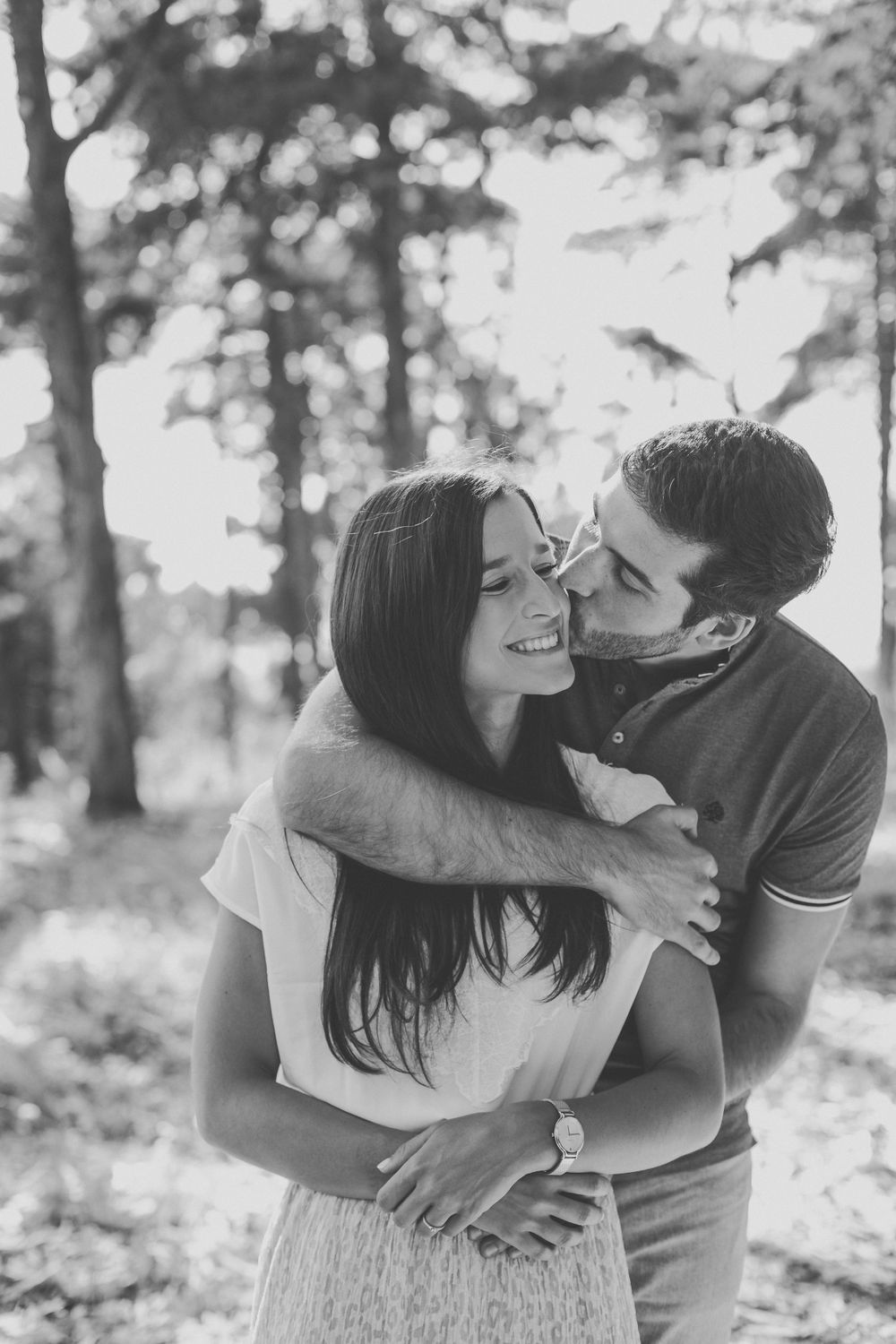Black and white photos capturing intimate embraces between a couple in a wooded setting.