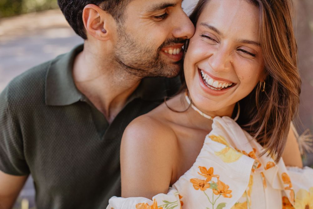 Candid moments of laughter and affection captured in natural outdoor lighting.