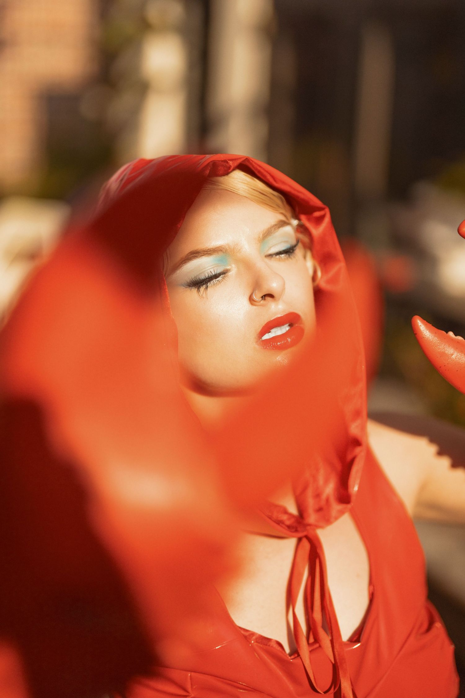 A dramatic portrait with a red veil and red lipstick in warm sunlight.