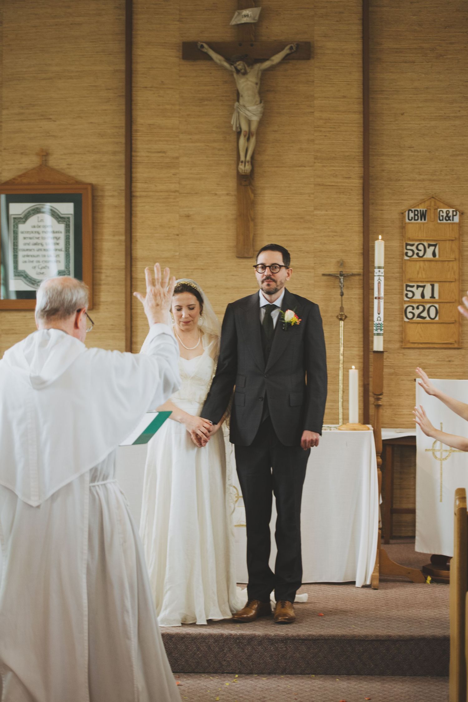A traditional Catholic church wedding ceremony taking place at the altar with a crucifix on the wall.