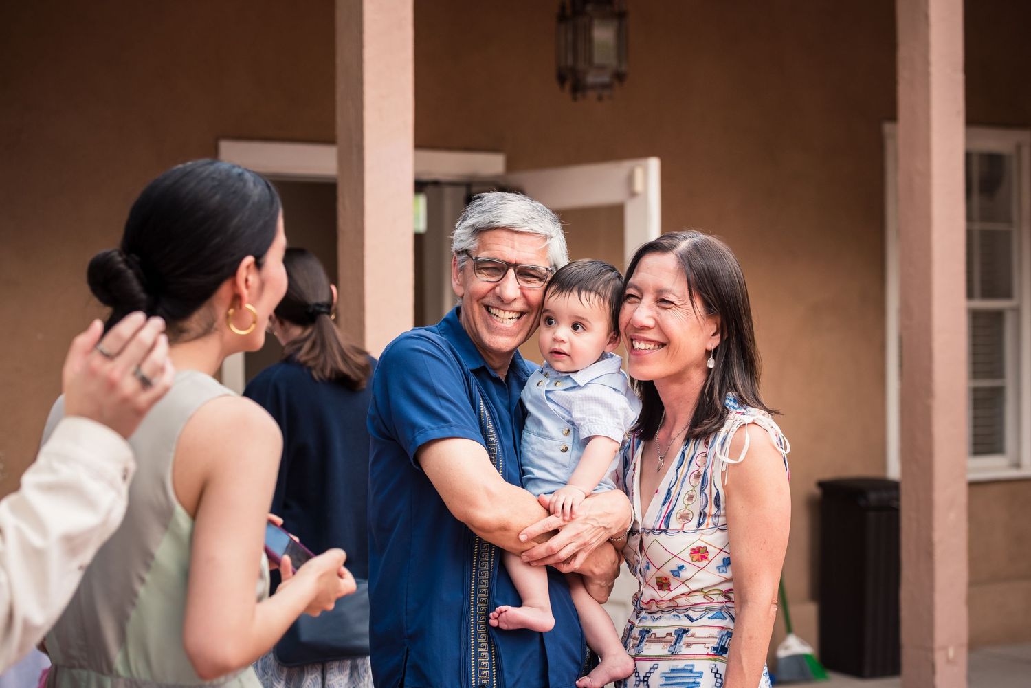 Casual gathering of people socializing outdoors at an adobe-style venue.