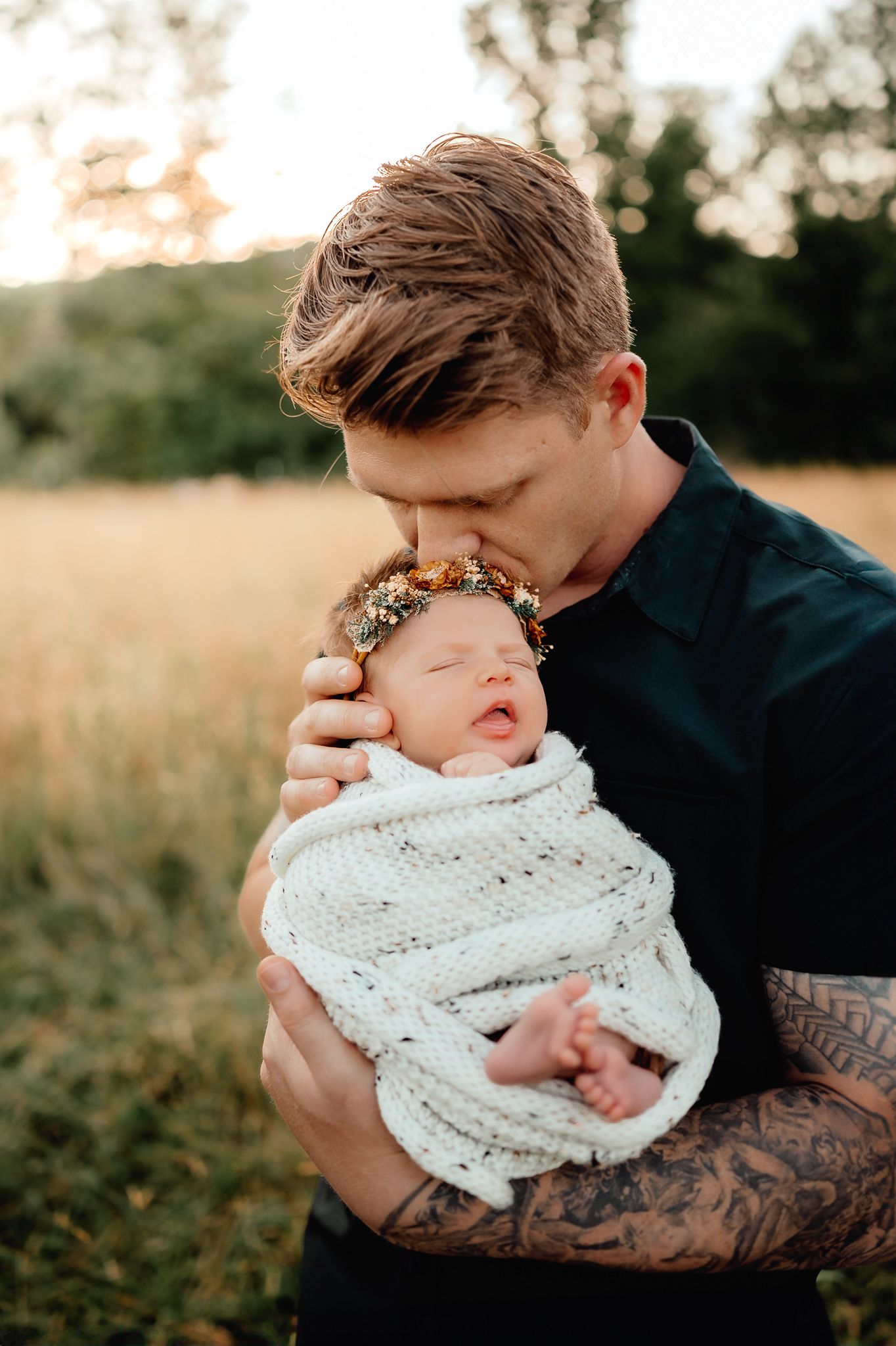 Tender moment between parent and newborn wrapped in knit blanket.