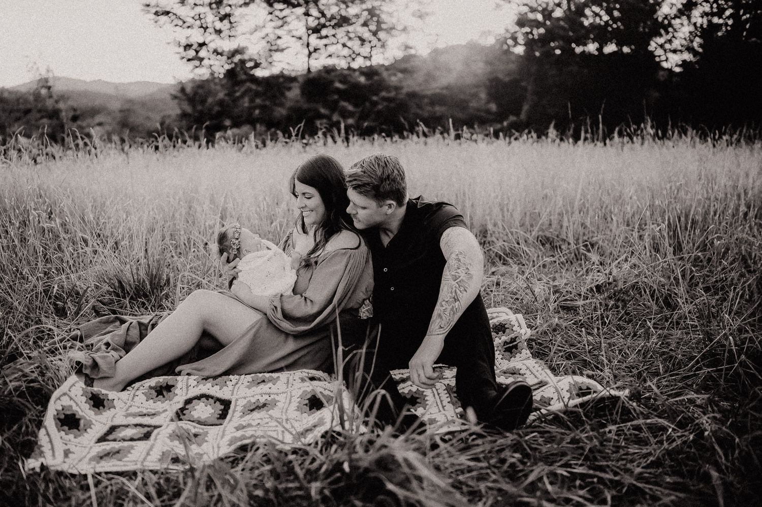 Black and white portrait of a couple sharing an intimate moment on a blanket outdoors.