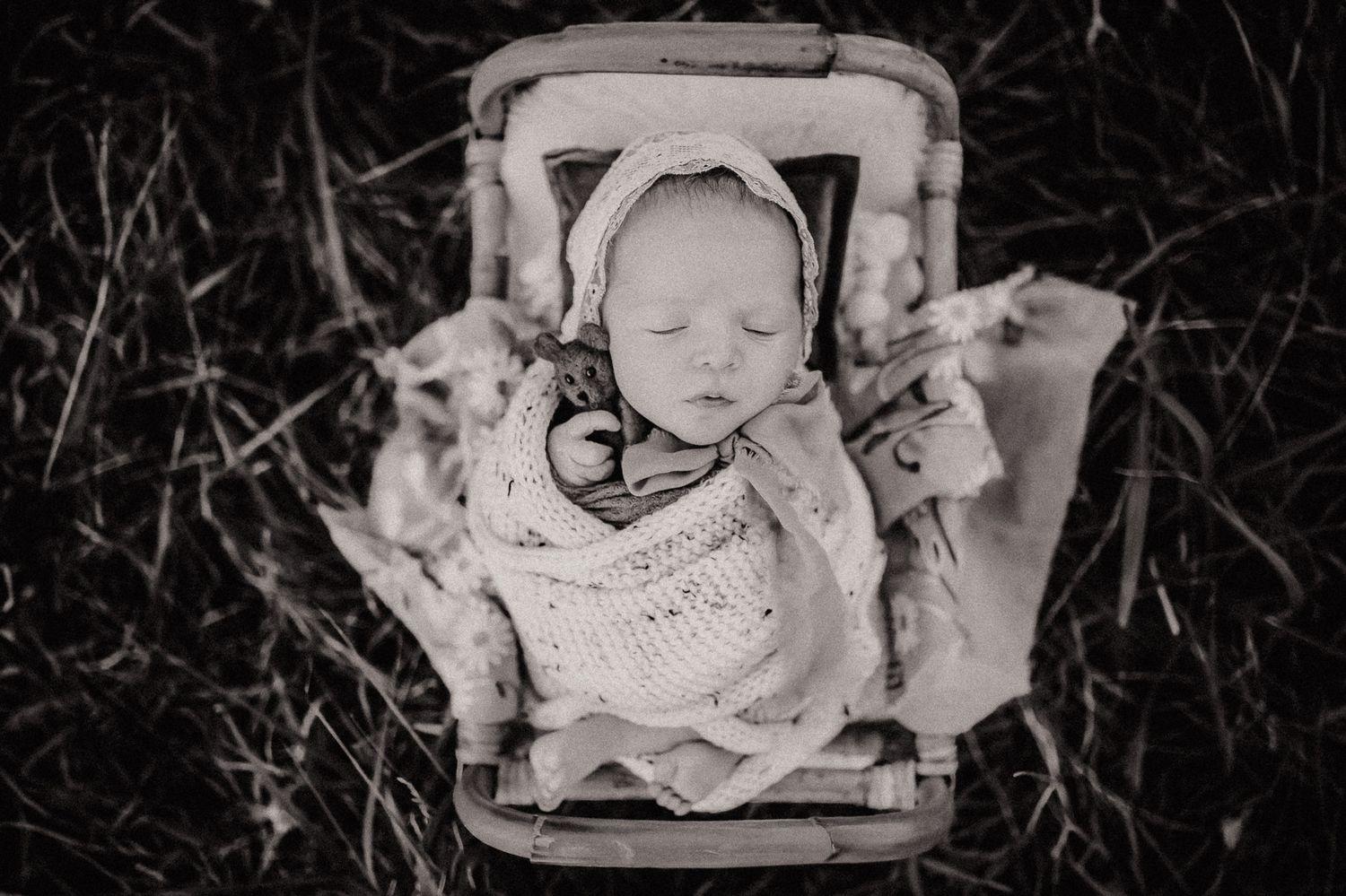 Black and white image of sleeping baby in vintage pram.