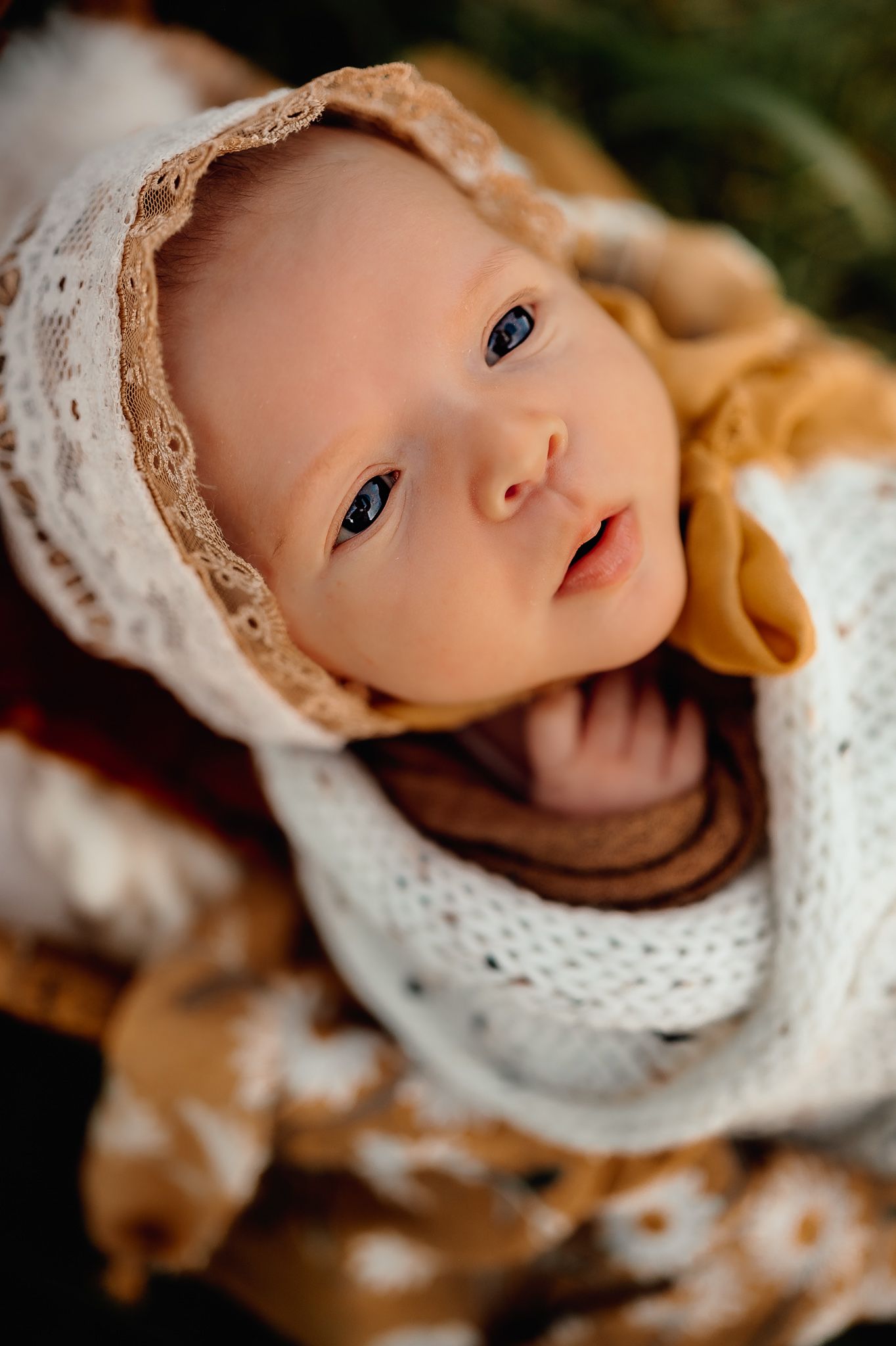 Close up of baby wearing vintage lace bonnet and white knit sweater.