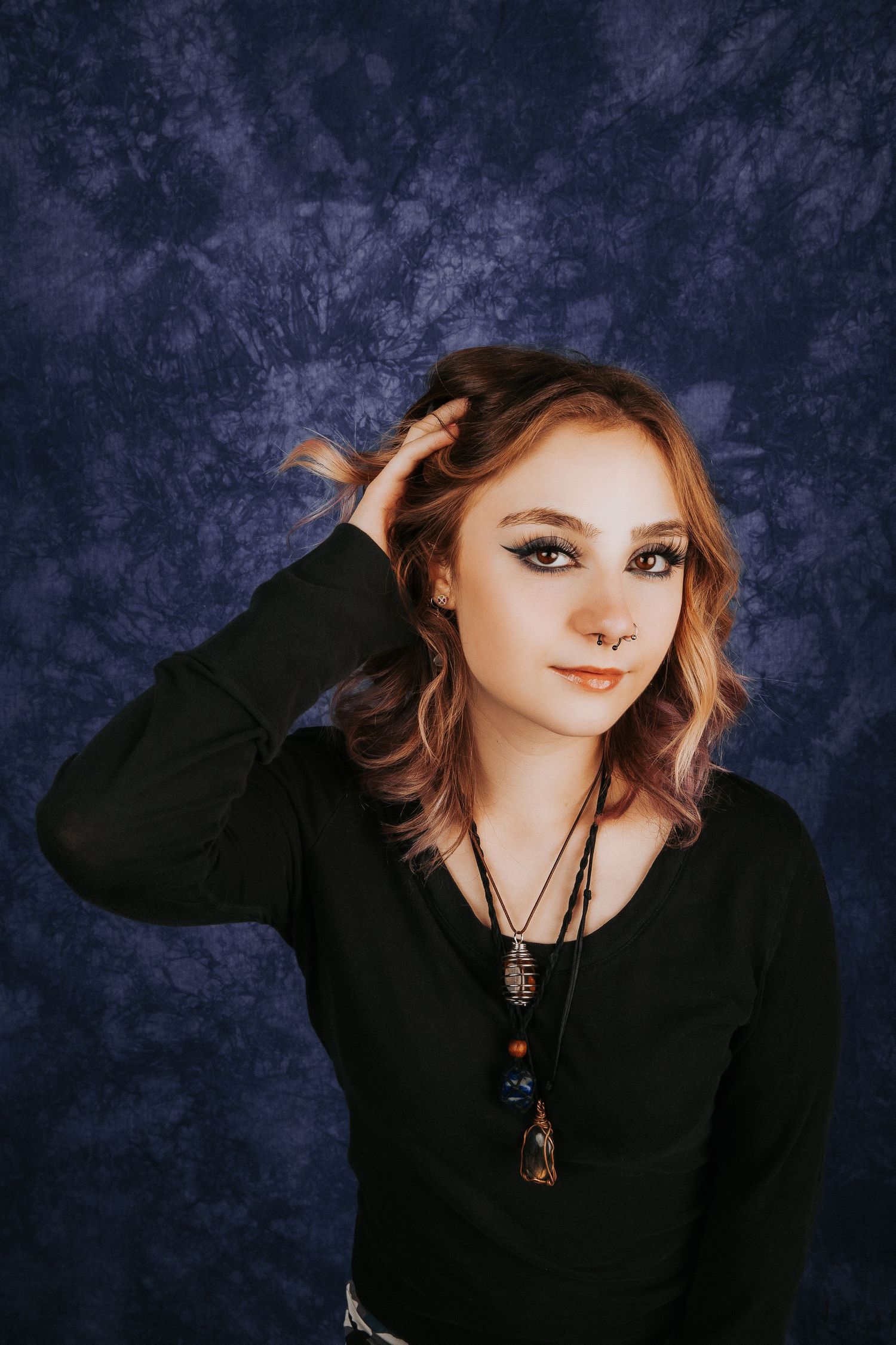 Stylish portrait series against navy backdrop featuring dark clothing and statement necklace.