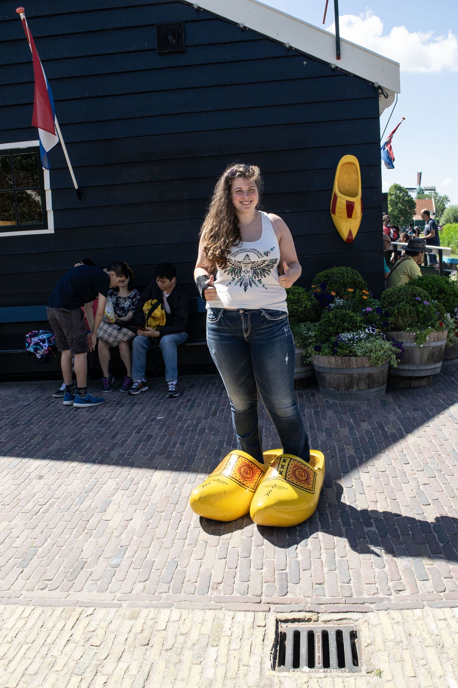 Giant yellow wooden clogs displayed outside a traditional Dutch building with brick pavement.