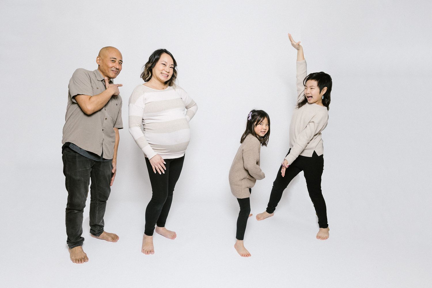 Family in coordinated outfits striking dynamic poses against white background.
