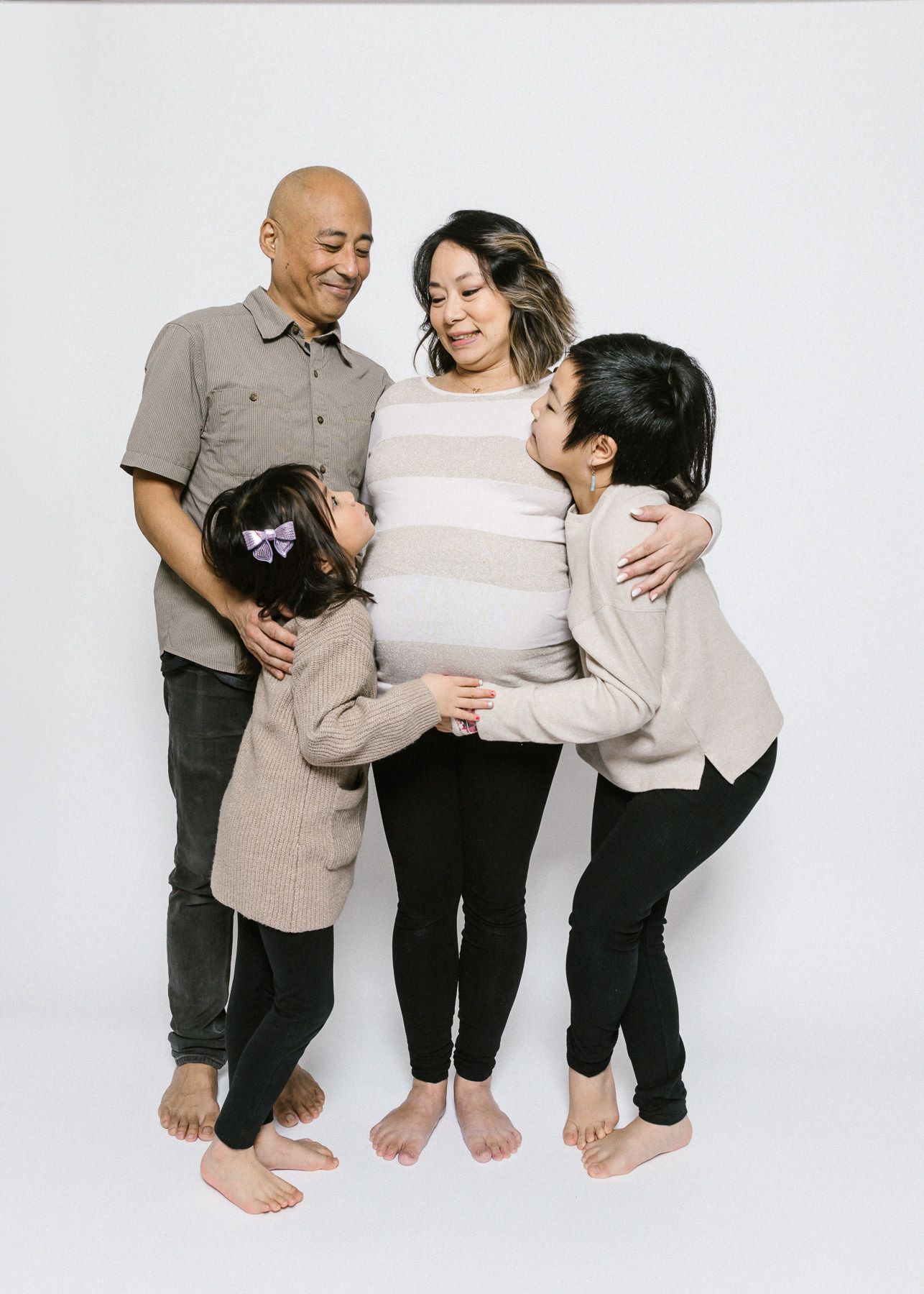 A loving family portrait with members gathered close together against a white backdrop.
