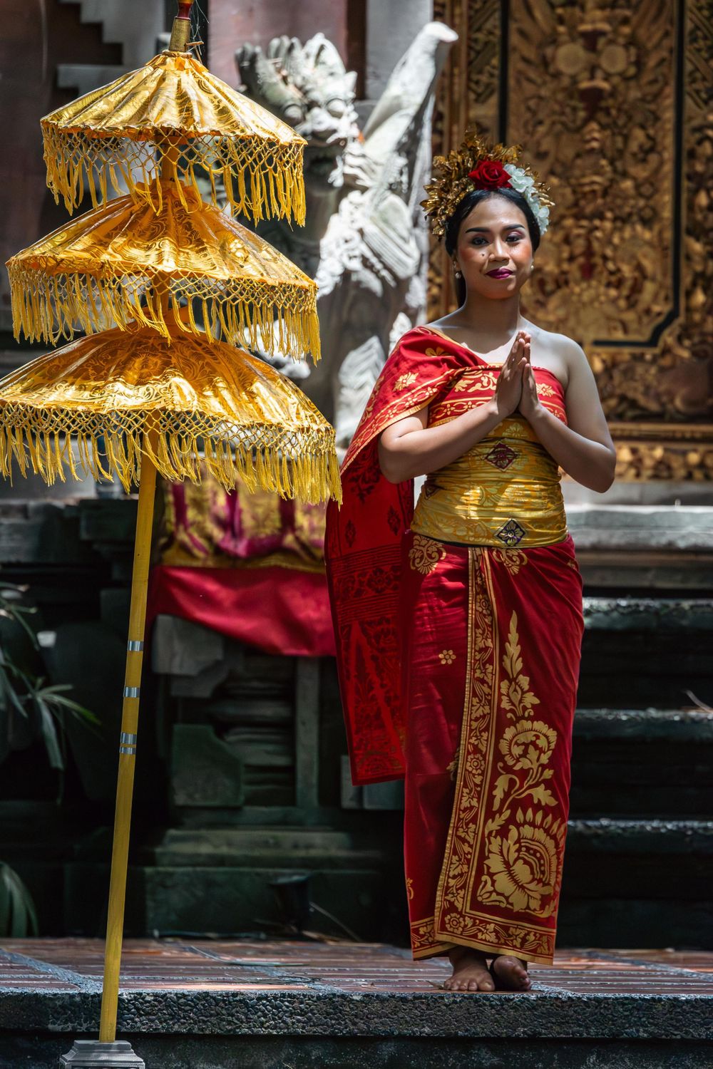 Traditional Balinese ceremony featuring ornate golden parasols and ceremonial dress in a temple setting.