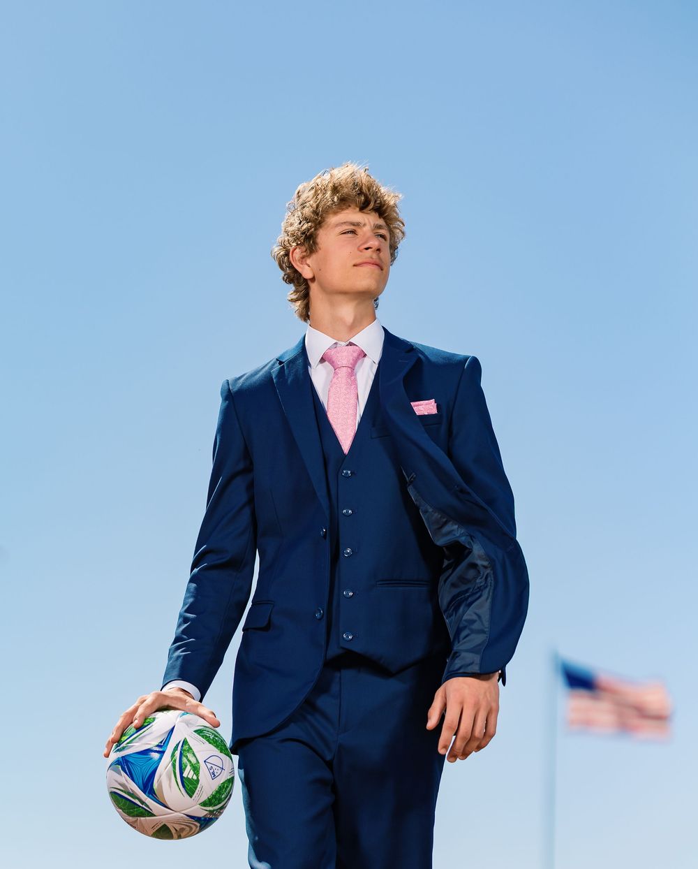 Tucson, AZ senior guy posing in a suit on the soccer field with a ball