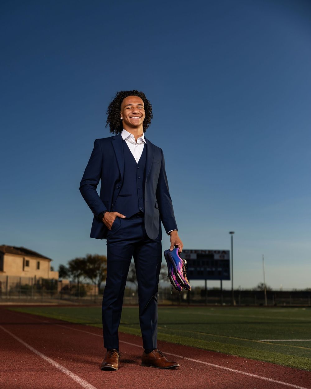 Tucson, AZ senior guy posing in a suit on the Cienega track with his spikes