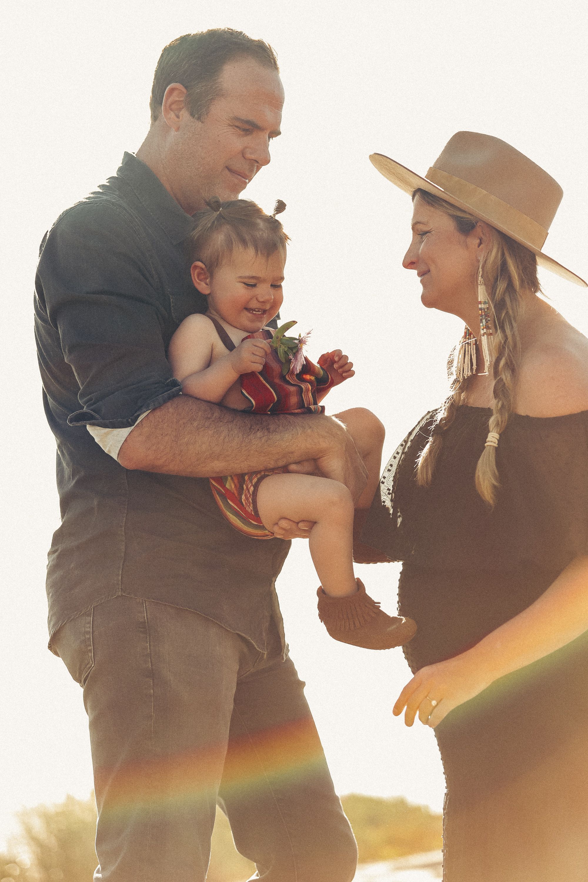 Family sharing tender moment together in warm sunset light.