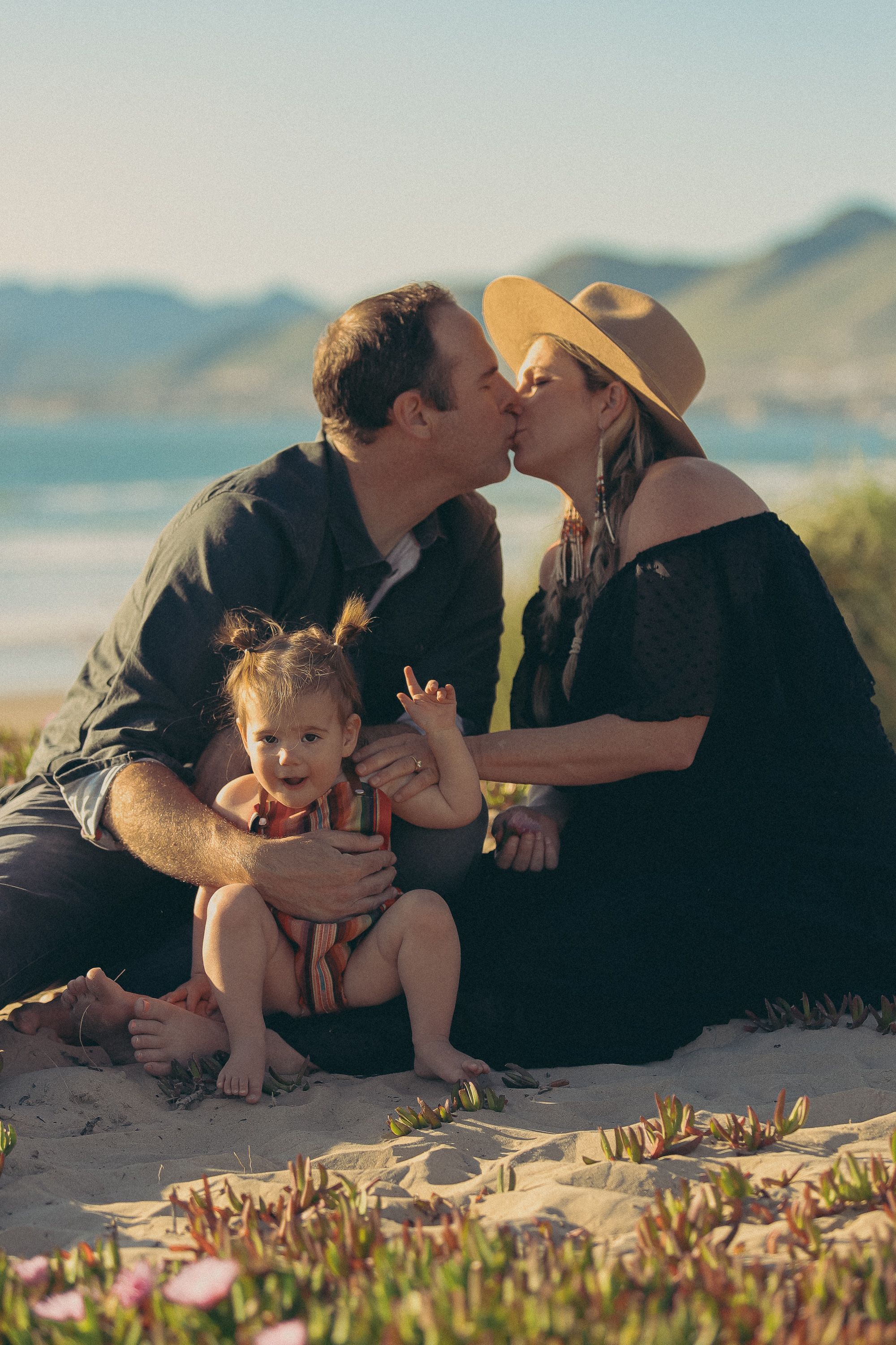 Family sharing a tender moment together on a scenic coastal hilltop.