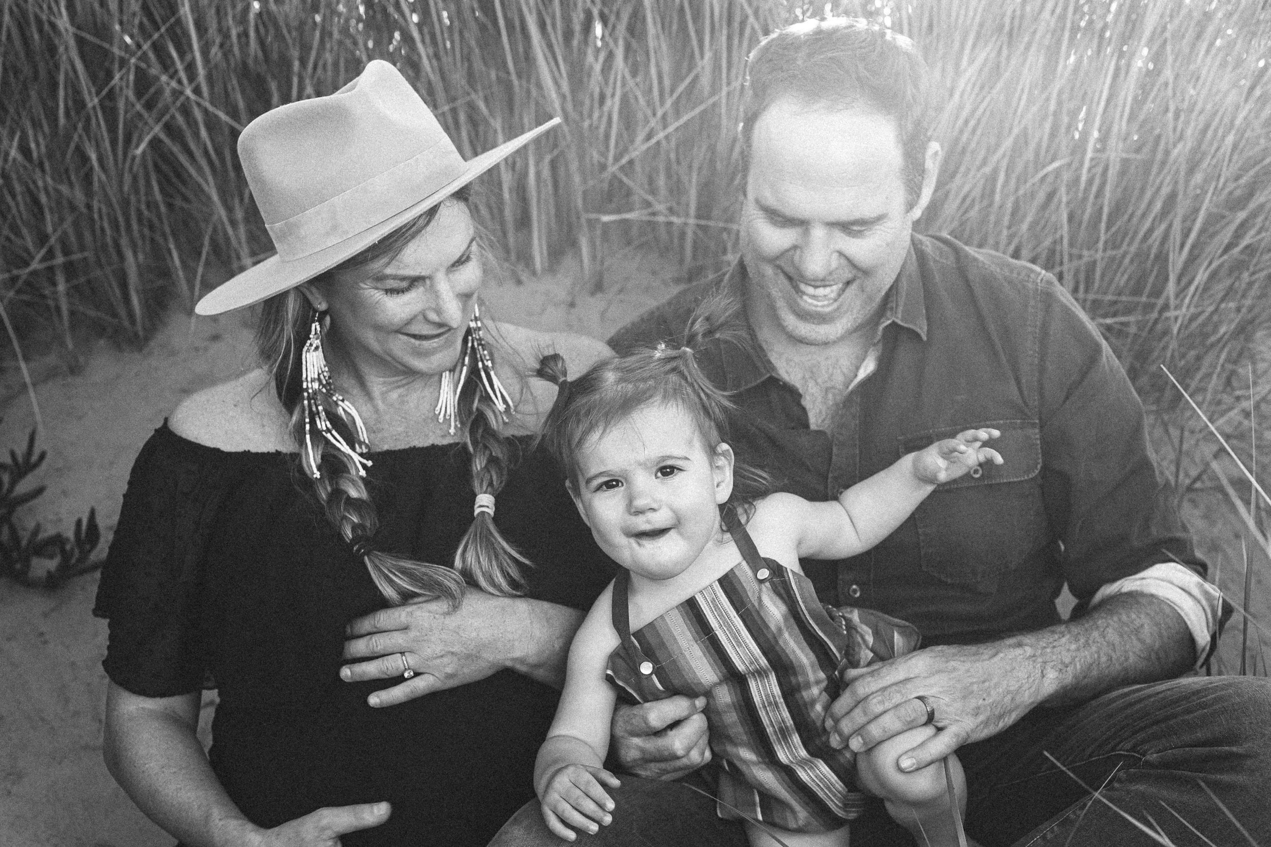Black and white photo of a family sharing laughs together in tall grass.