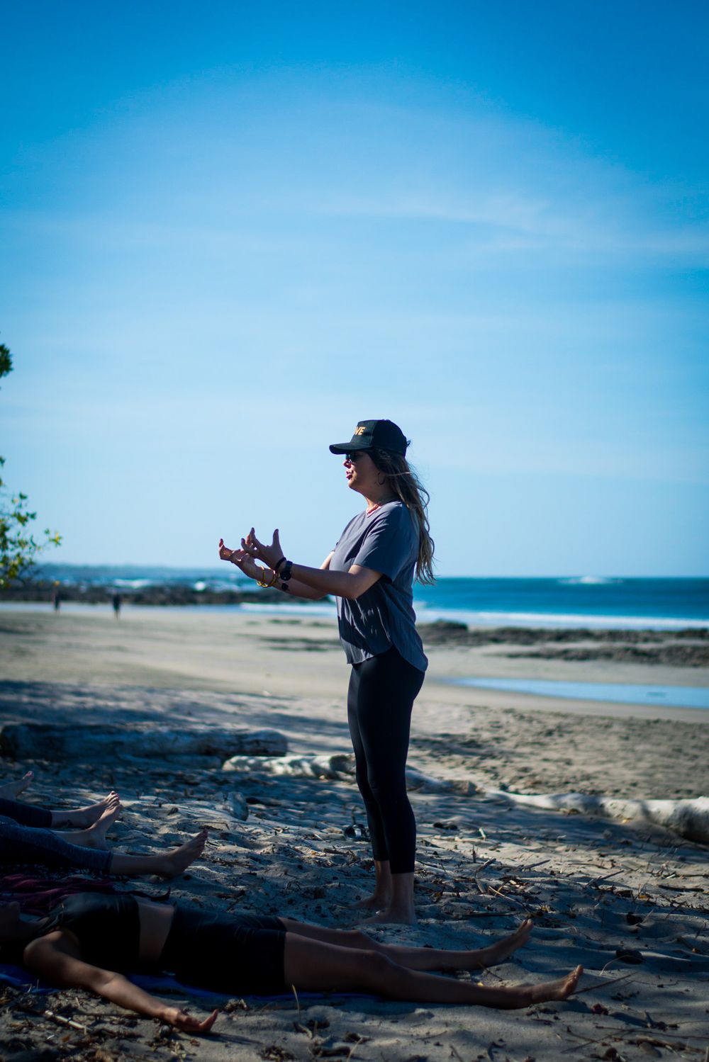 Instructor leading beach yoga session with ocean waves in background.