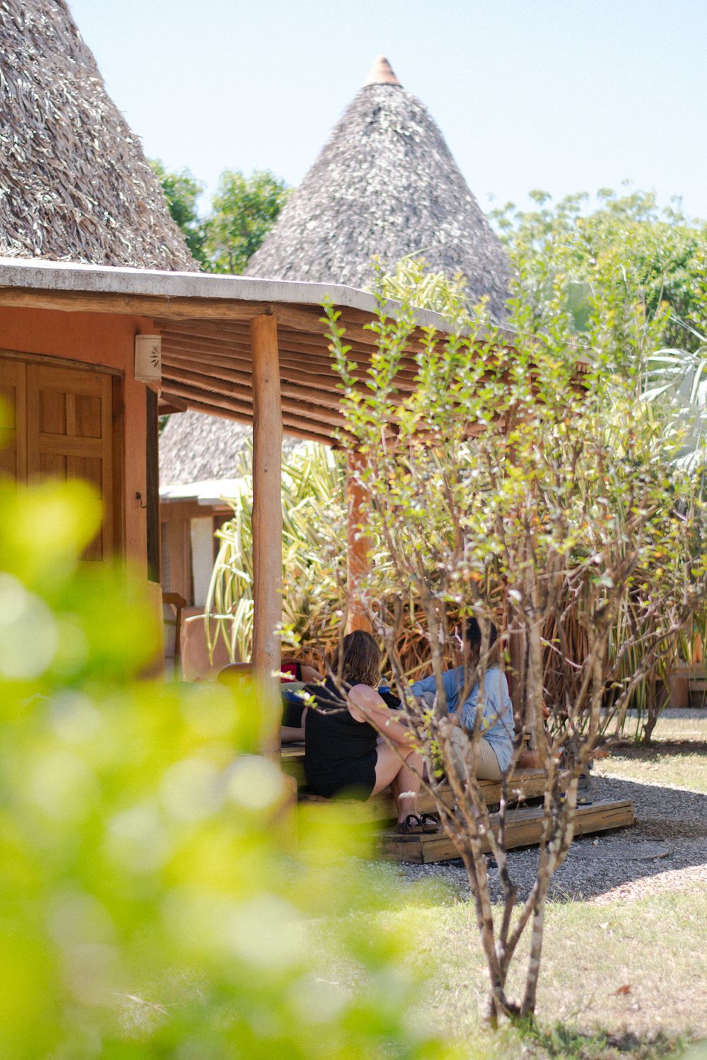 Rustic thatched-roof meditation pavilion surrounded by lush greenery.