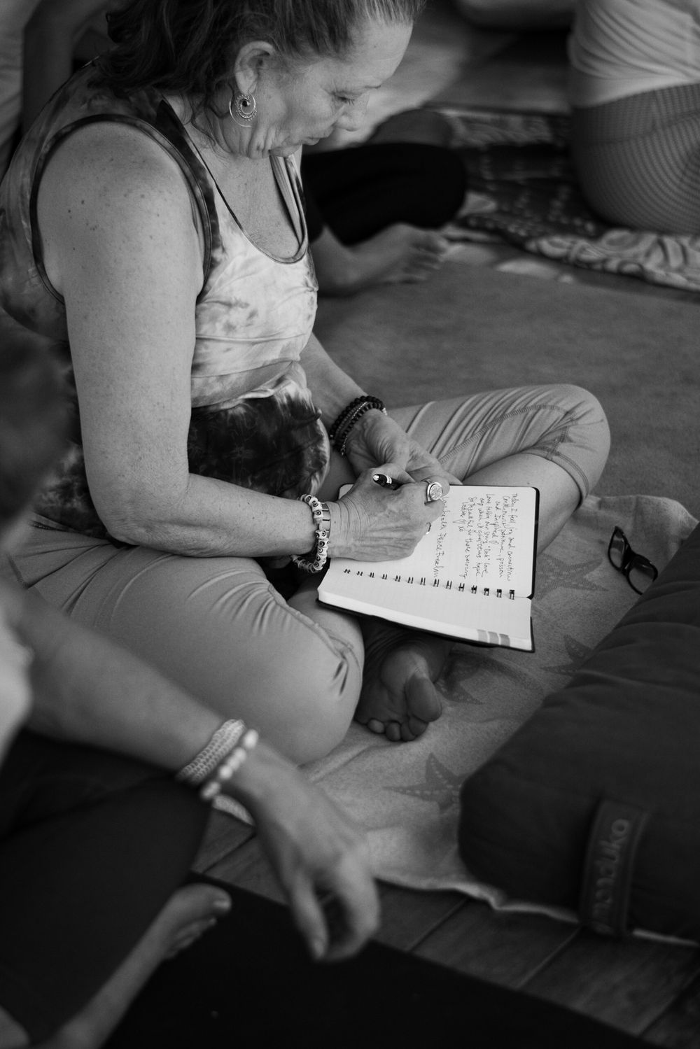 Person writing in journal during meditation retreat in black and white.