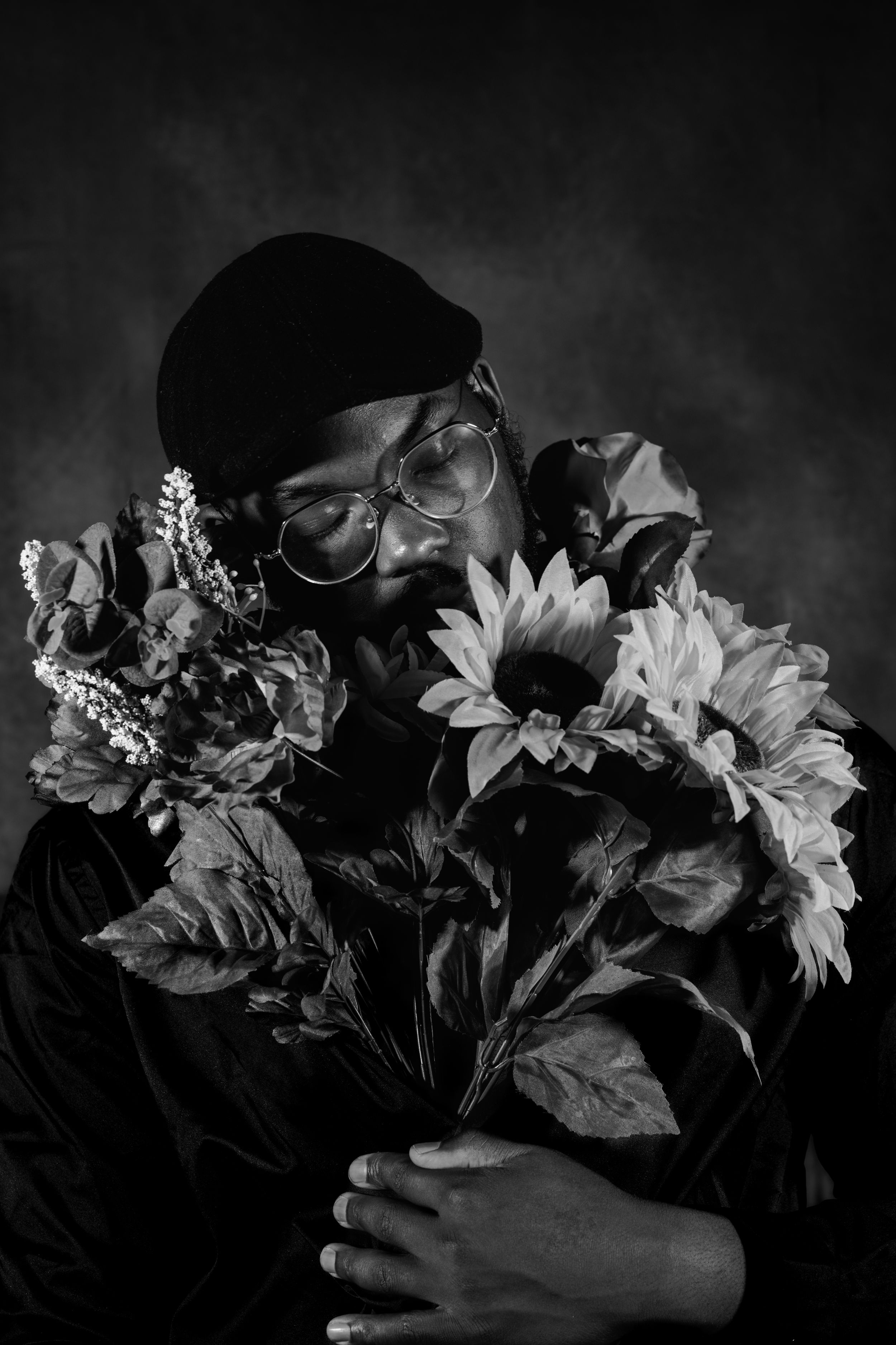 Person in dark clothing embracing a bouquet of white flowers in dramatic black and white photography.