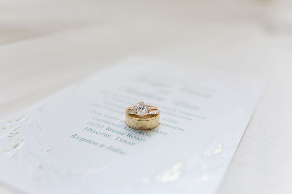 Diamond wedding ring photographed on white invitation paper.