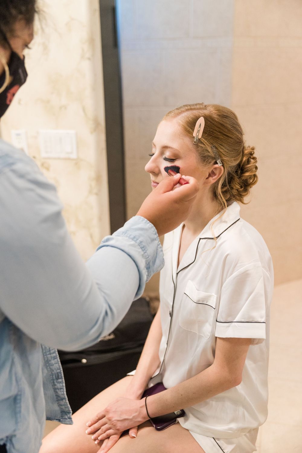 Makeup artist applying cosmetics to bride during wedding preparation.