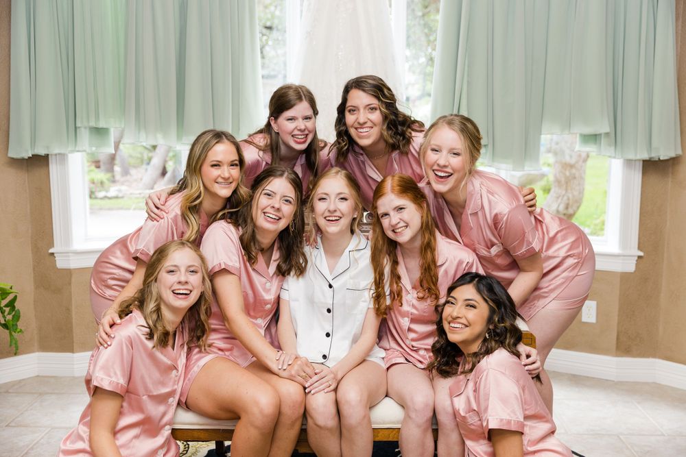 Bridal party in matching pink robes posing together before wedding ceremony.