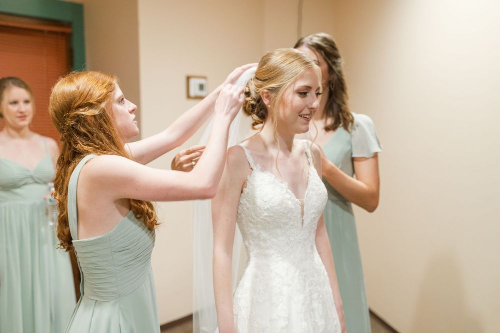 Bridesmaids in mint green dresses help with final wedding preparations.