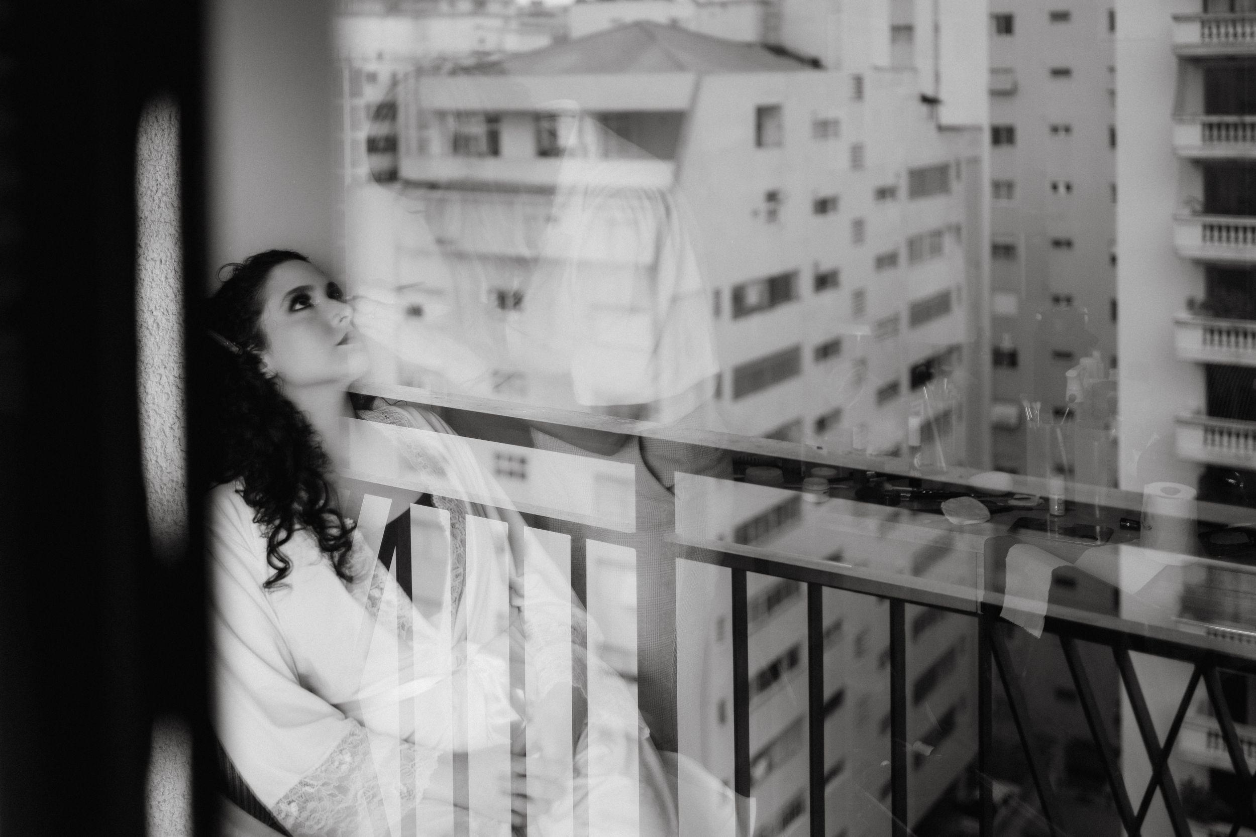 Artistic black and white photo of a person on an urban balcony.