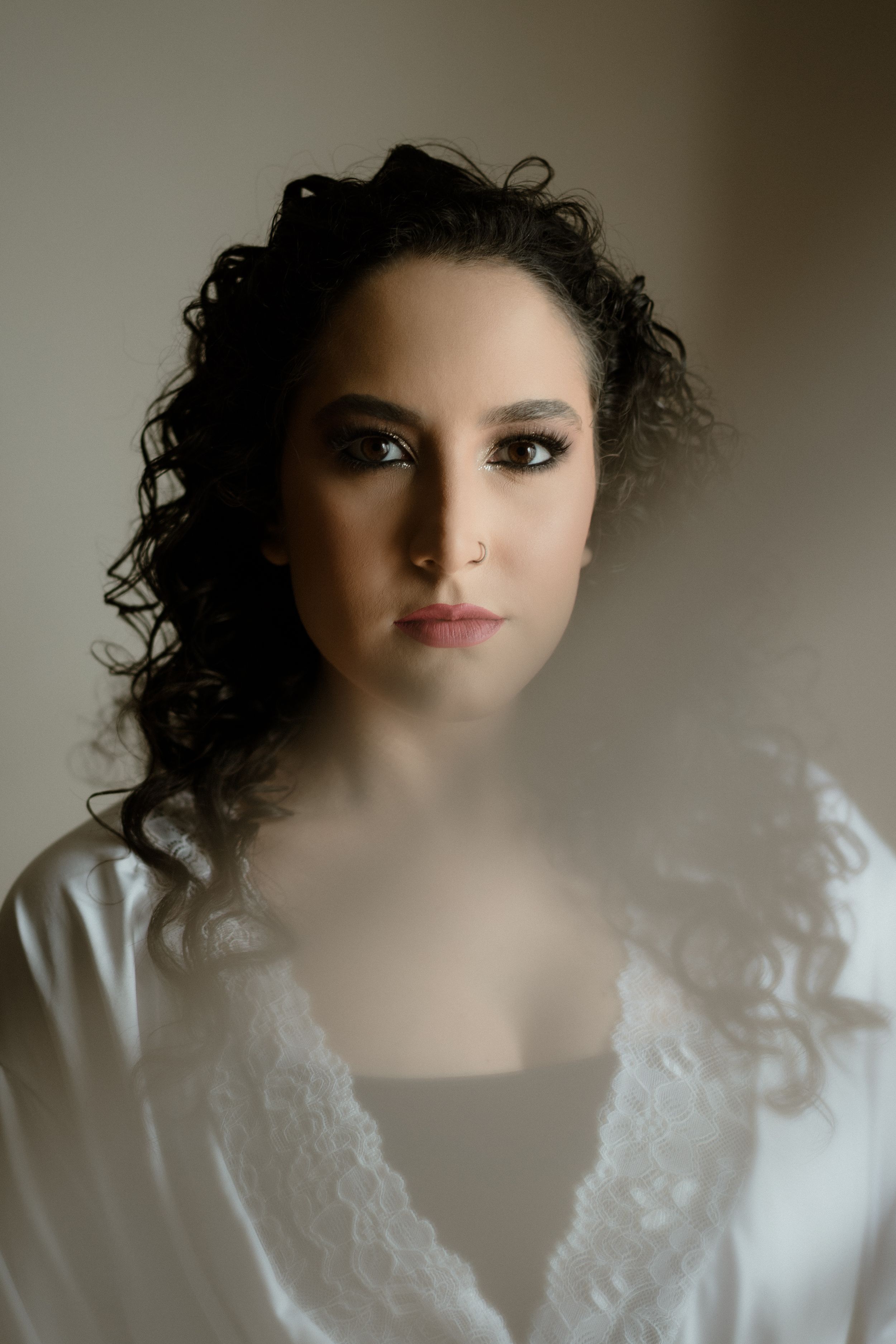 Soft portrait with dramatic lighting against neutral background.