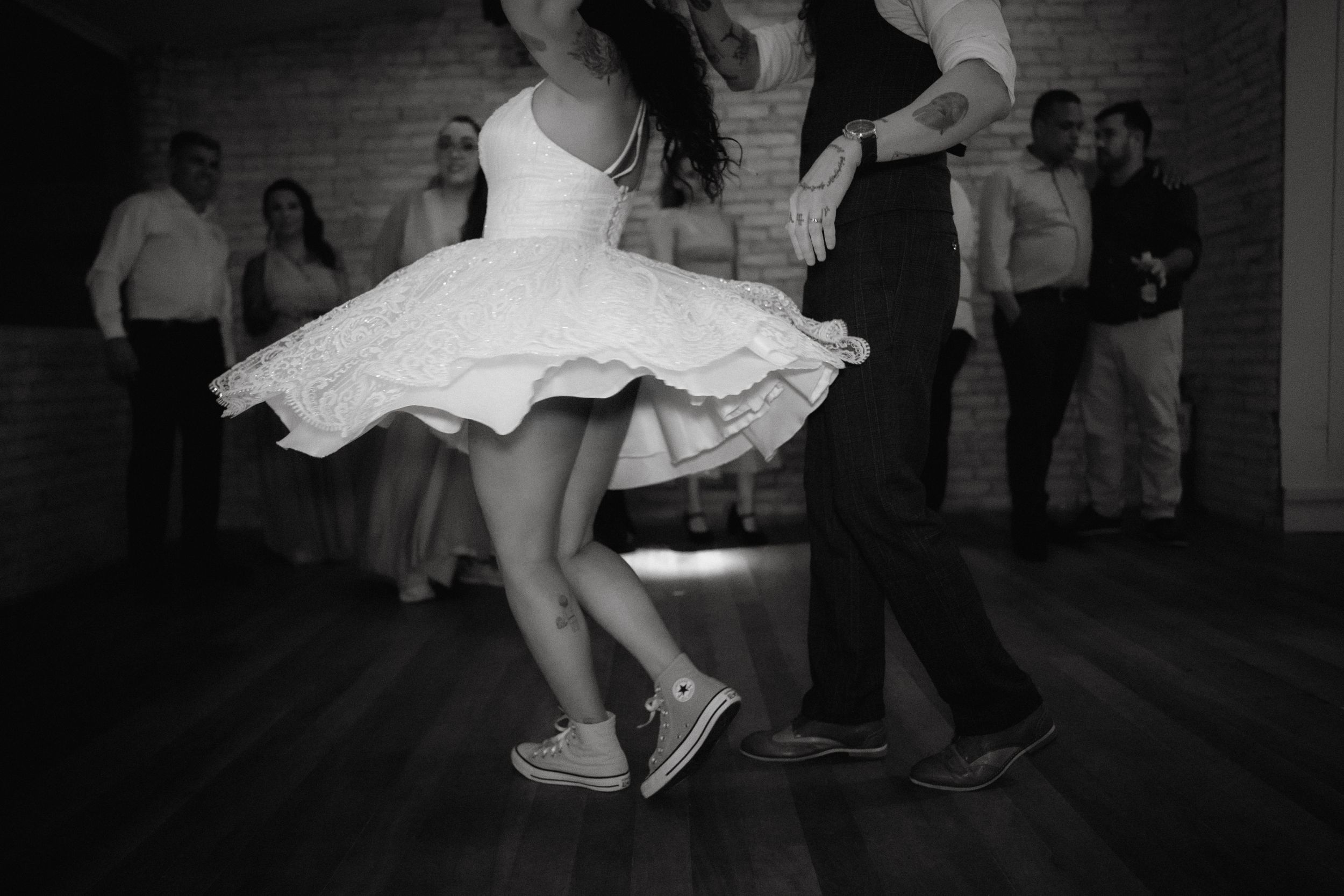Black and white image of dancing feet and dress hems at a wedding reception.