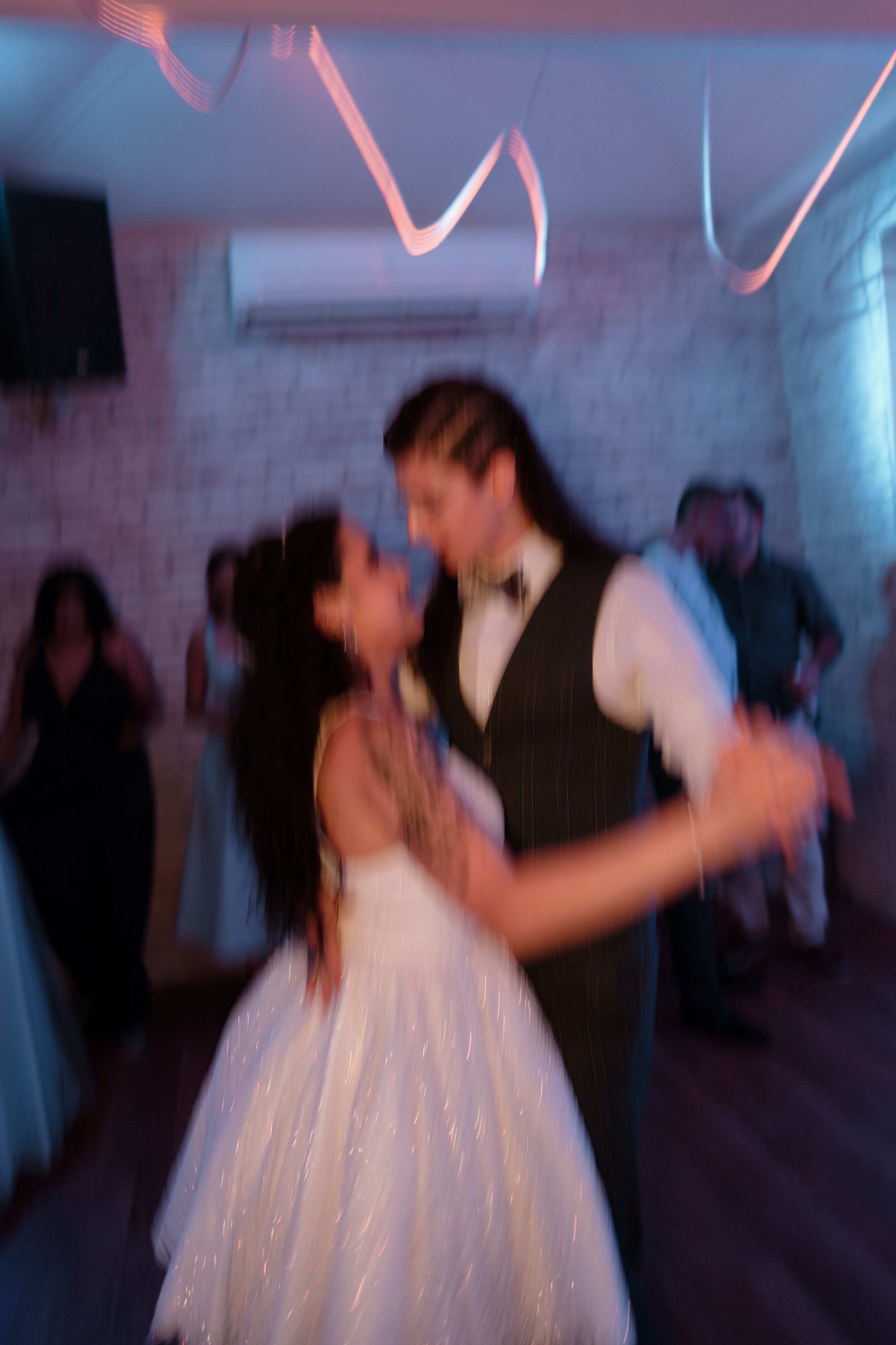 Motion-blurred photo of dancers in white dress twirling on a dance floor.