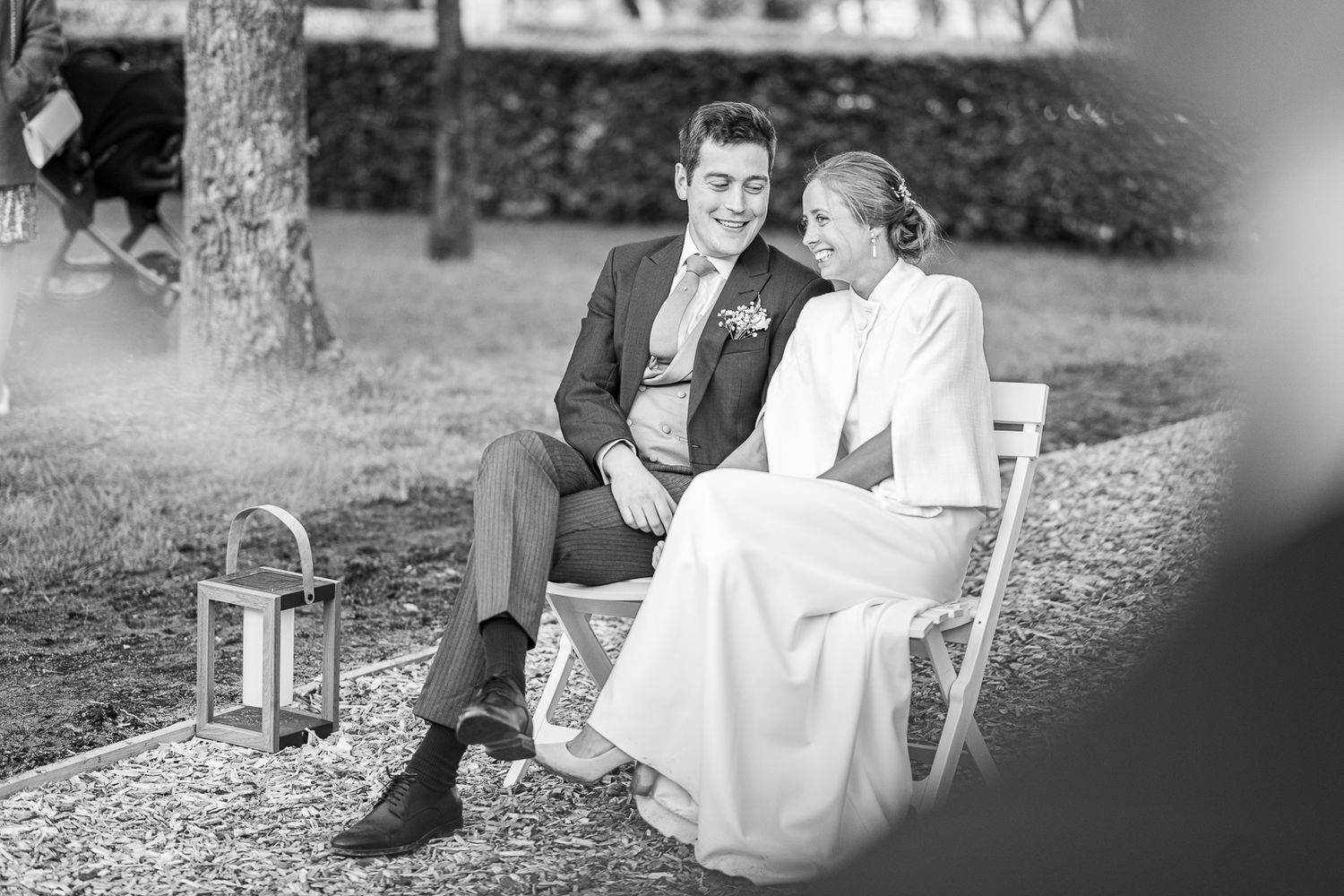 A vintage black and white photo of a couple sitting together outdoors with a lantern beside them.