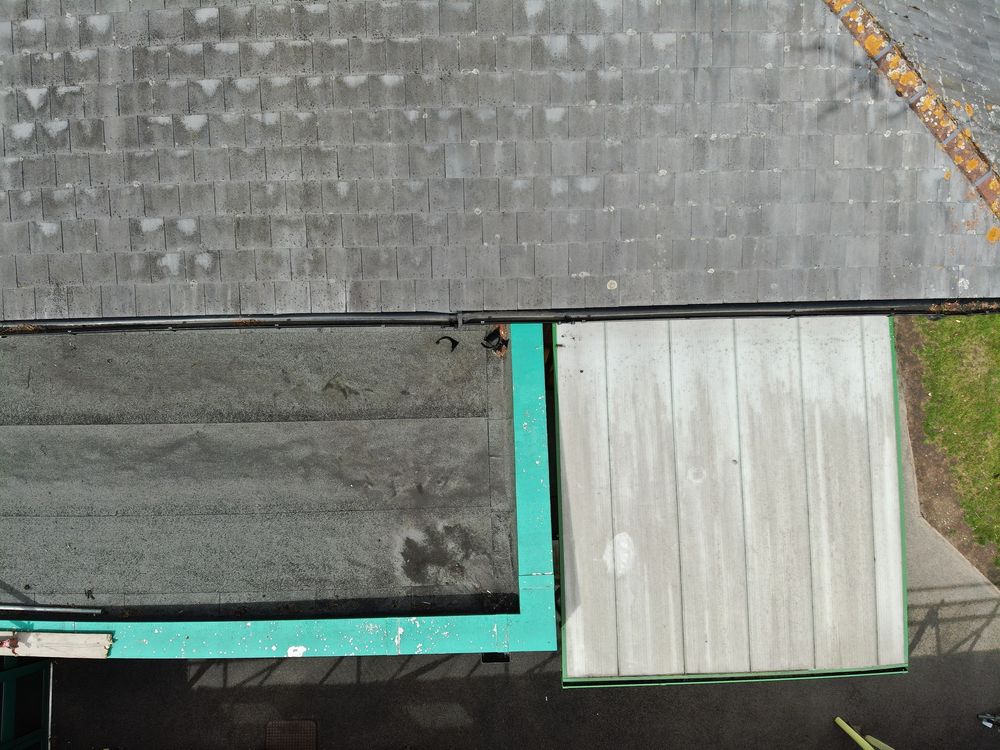 Aerial view of a gray rooftop with teal trim and a white wooden door panel.