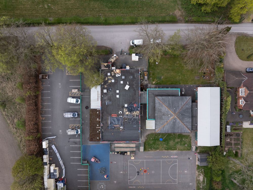 An aerial drone view of an empty parking lot near a community center and basketball court.