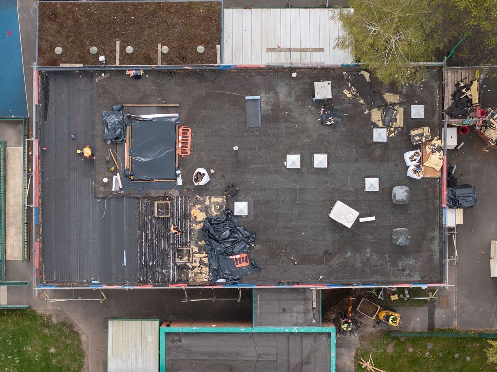 Aerial view of a commercial rooftop with scattered debris, equipment, and maintenance materials.