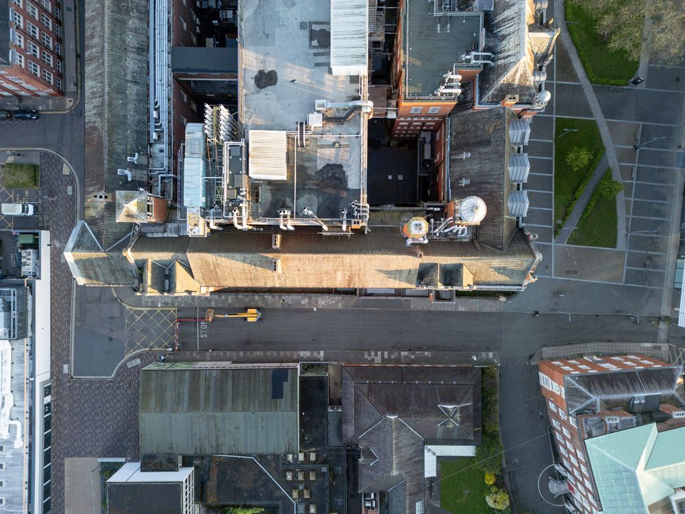 Aerial view of downtown city streets with tall buildings and rooftop infrastructure from directly above.