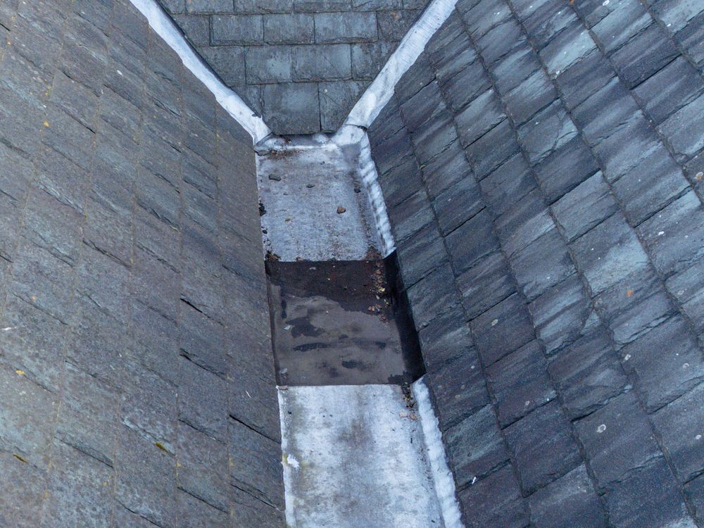 View looking up at converging walls and gutters on the exterior of a building structure showing drainage patterns.