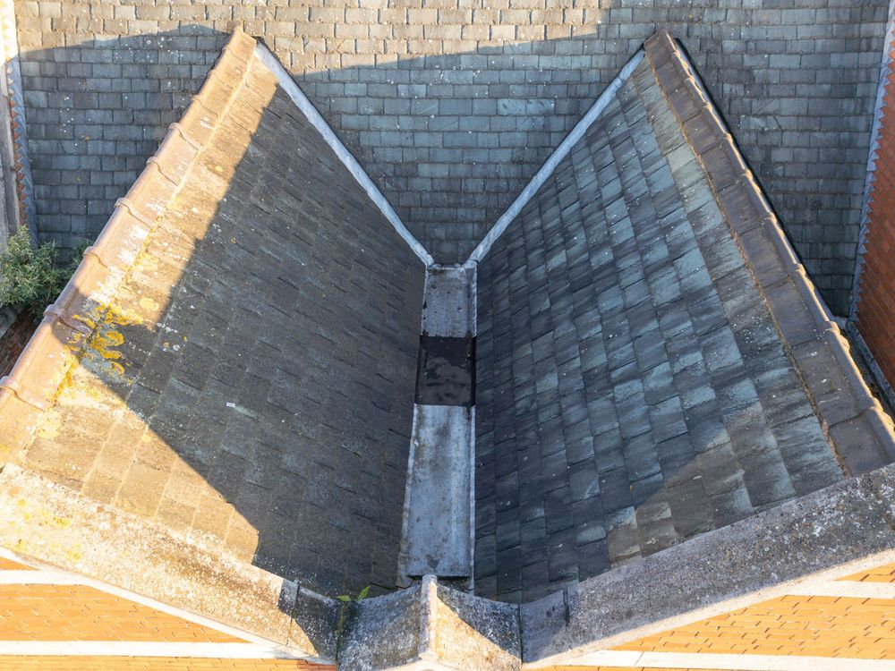 Close-up view of worn asphalt roof shingles showing signs of damage and weathering along the edges.
