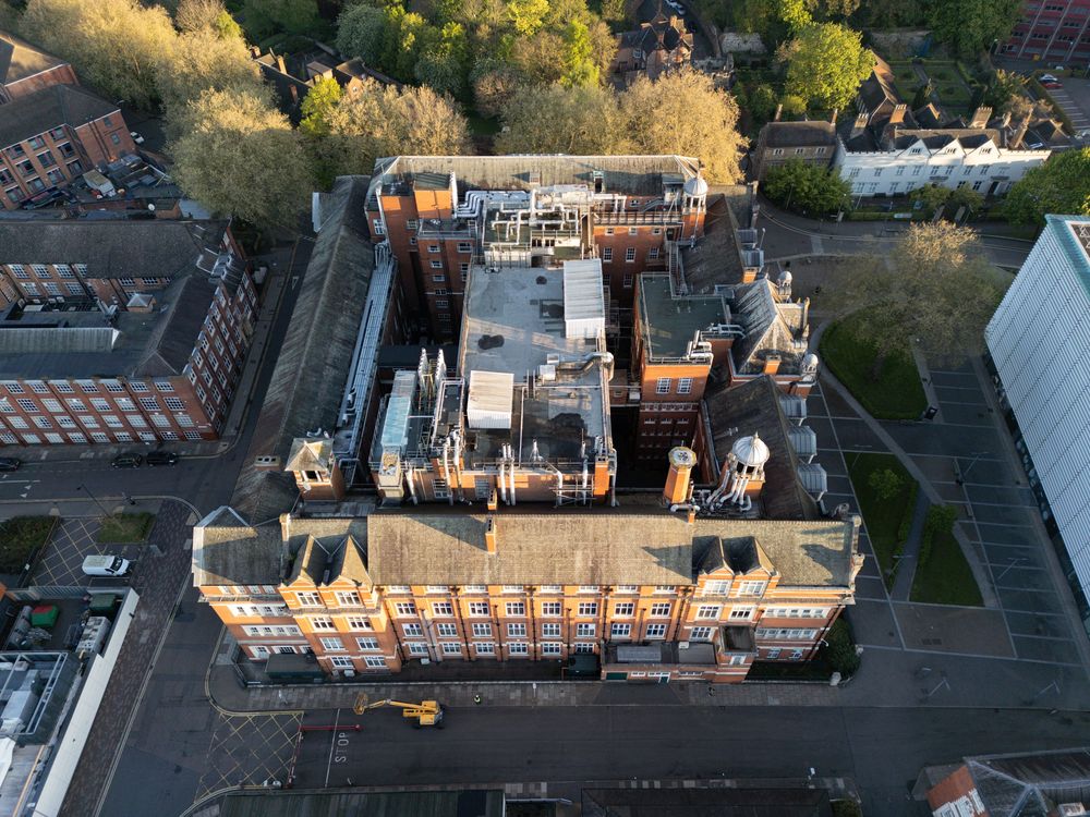 Aerial view of a historic brick building with Victorian architecture and ornate details under golden sunlight.