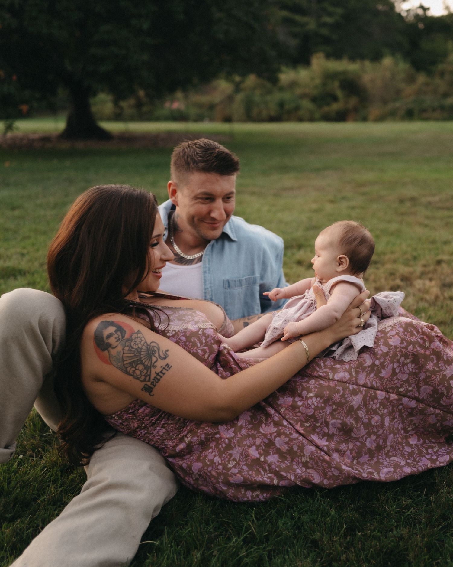 A family shares tender moments while relaxing together on a grassy lawn during a summer afternoon.