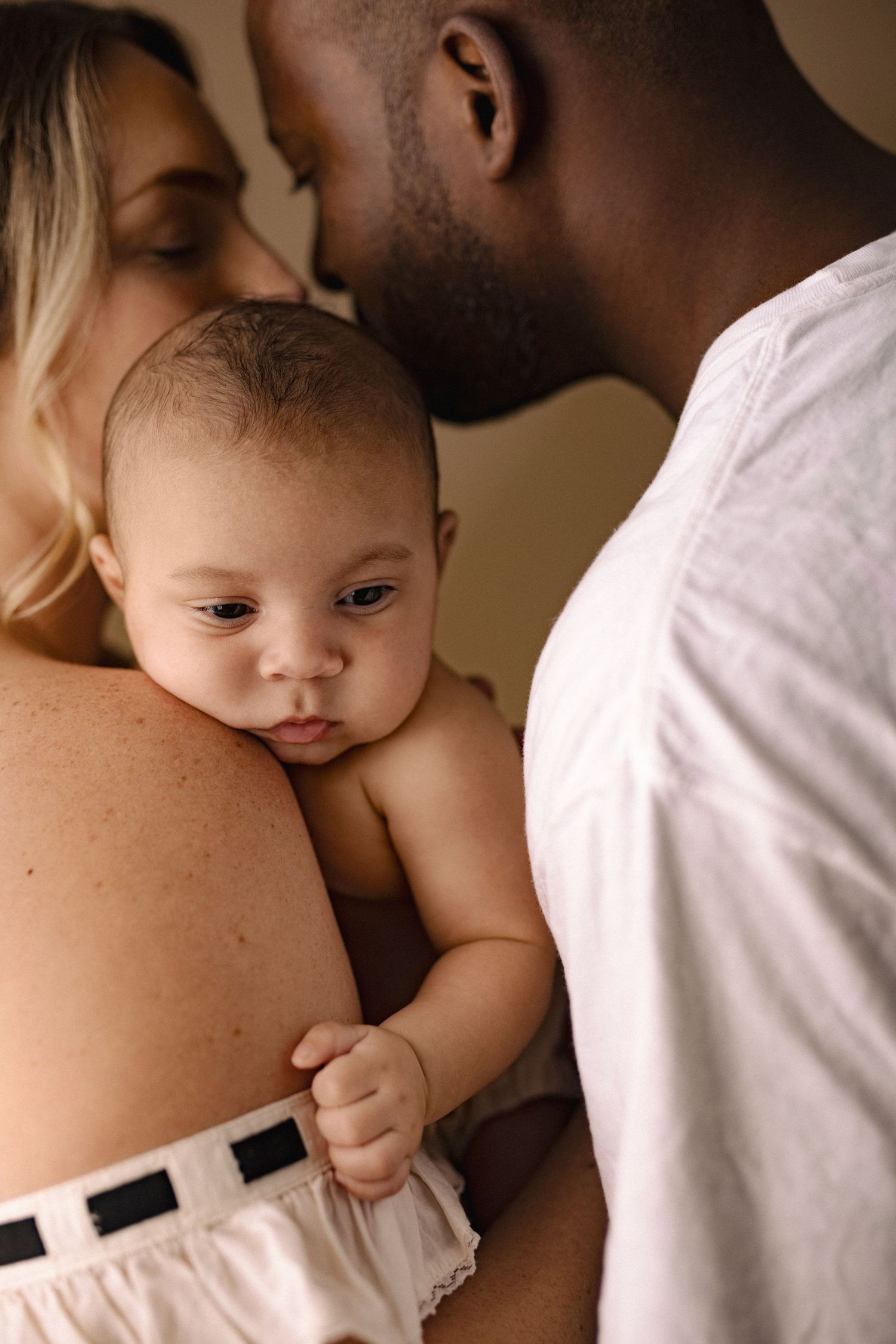 A series of intimate photos showing a baby resting against someone wearing a white shirt in warm, sepia-toned lighting.