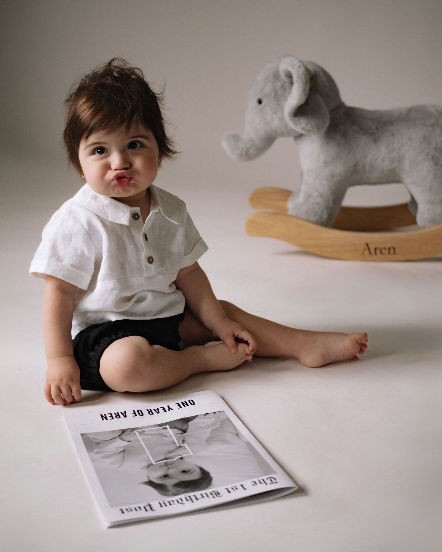 Studio photo of child sitting on floor with plush rocking horse and photograph.
